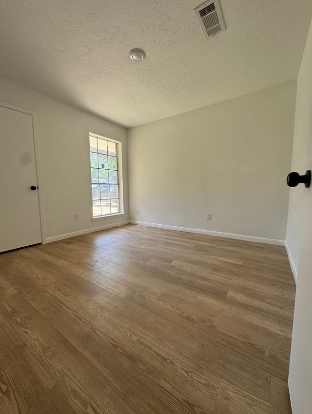 7810 Bunker Wood Ln, Houston, TX 77086 - spare room with a textured ceiling, baseboards, visible vents, and wood finished floors