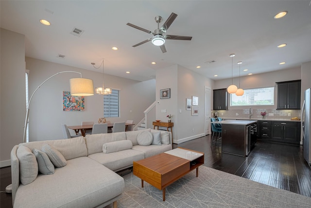 living area with visible vents, stairs, ceiling fan with notable chandelier, dark wood-style floors, and recessed lighting