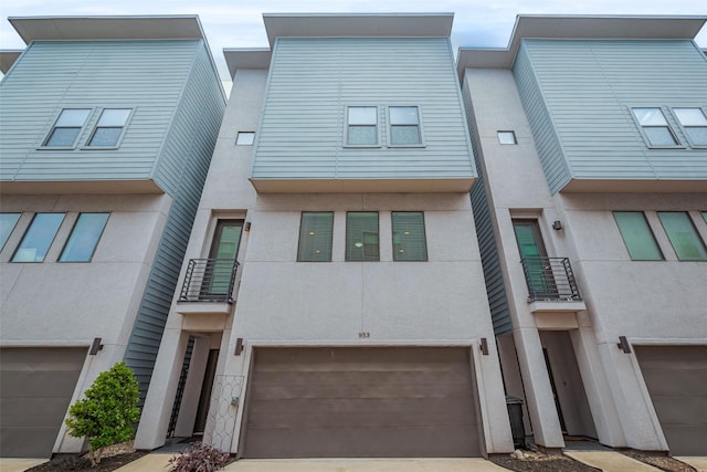 multi unit property with an attached garage, stucco siding, a balcony, and concrete driveway
