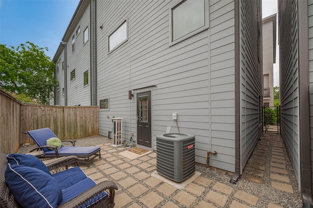 rear view of property with central AC, a fenced backyard, and a patio area