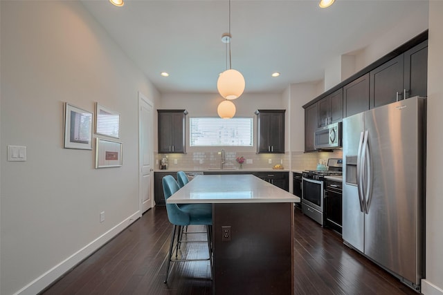 kitchen featuring a kitchen bar, light countertops, a sink, appliances with stainless steel finishes, and backsplash
