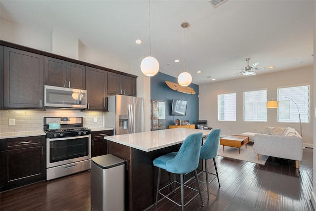 kitchen with light countertops, a breakfast bar area, stainless steel appliances, open floor plan, and tasteful backsplash