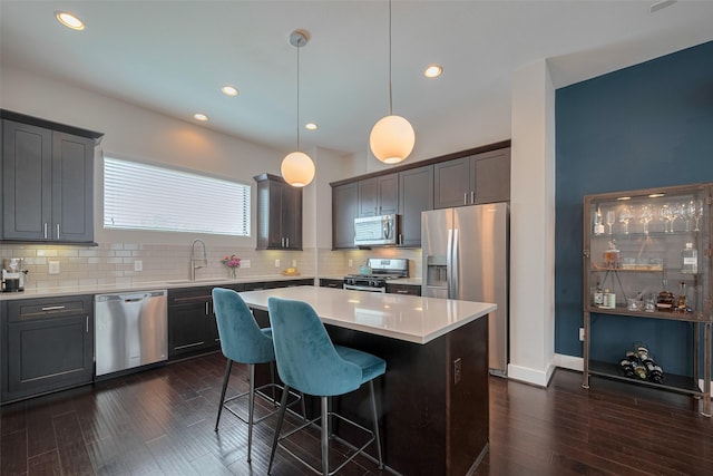 kitchen featuring a sink, dark wood finished floors, a center island, stainless steel appliances, and decorative backsplash