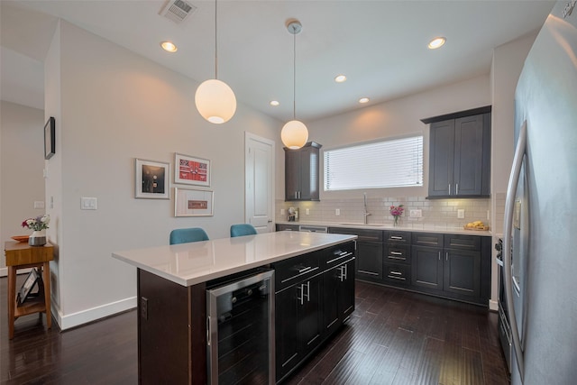 kitchen featuring dark wood-style flooring, visible vents, a sink, freestanding refrigerator, and beverage cooler