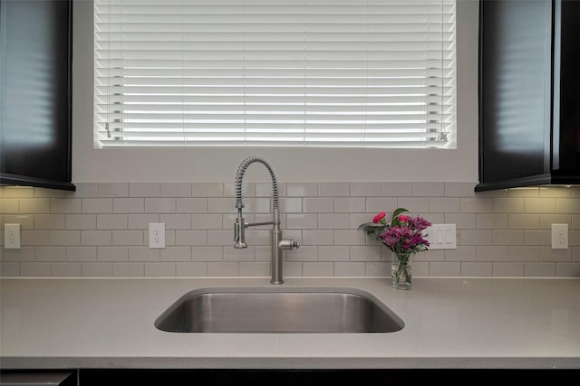 kitchen with a sink, light countertops, tasteful backsplash, and plenty of natural light