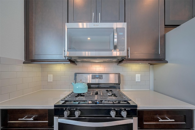 kitchen with range with gas stovetop, dark brown cabinets, light countertops, stainless steel microwave, and backsplash