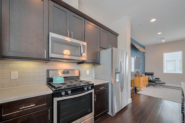 kitchen featuring decorative backsplash, light countertops, baseboards, dark wood-style floors, and stainless steel appliances