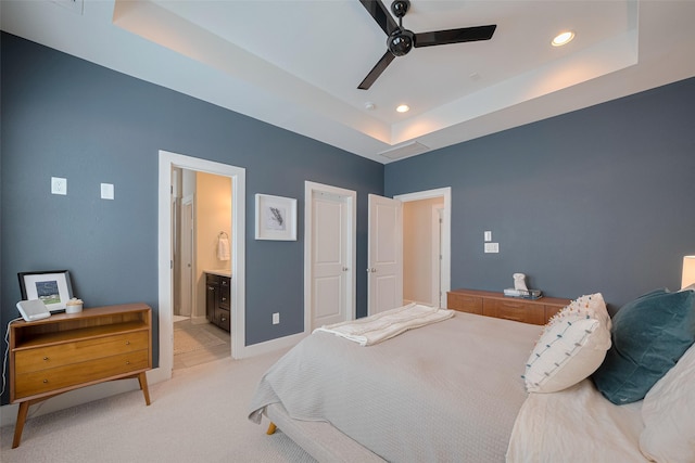 bedroom featuring recessed lighting, ensuite bathroom, a tray ceiling, and light colored carpet