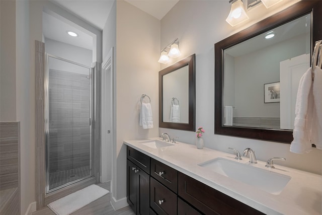 bathroom with double vanity, recessed lighting, a shower stall, and a sink