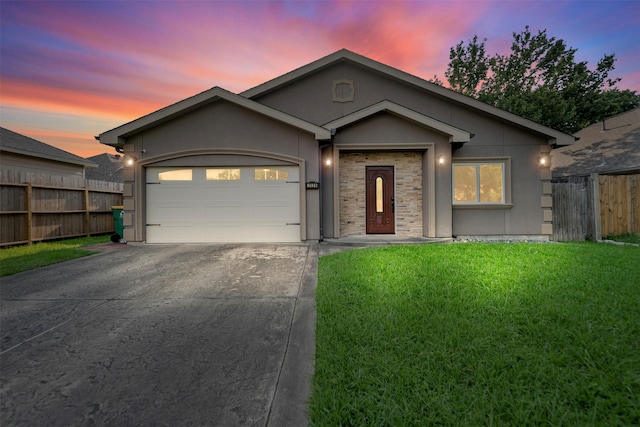 ranch-style house with an attached garage, fence, stucco siding, a lawn, and driveway