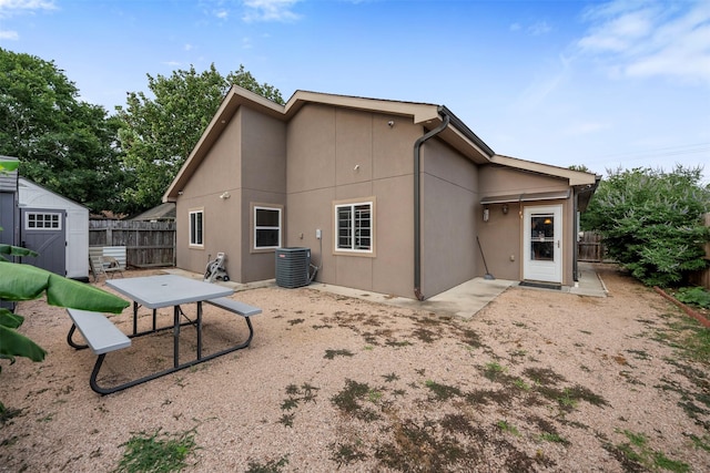 back of property featuring a patio area, central AC, an outdoor structure, a fenced backyard, and a storage unit