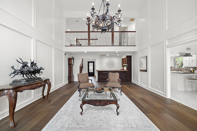 dining room with ornamental molding, a decorative wall, and dark wood-style floors