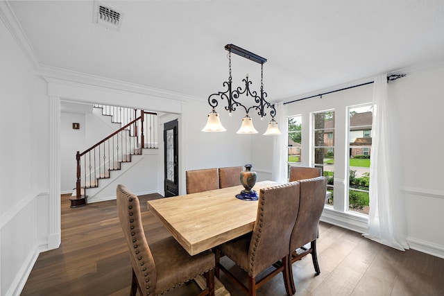 dining room with visible vents, crown molding, wood finished floors, and stairway