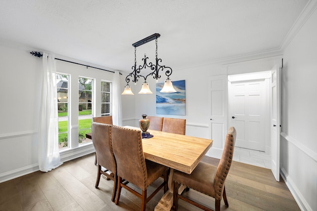 dining space featuring baseboards, ornamental molding, and light wood-type flooring