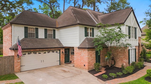 view of front facade featuring driveway, brick siding, fence, an attached garage, and stucco siding