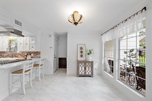 dining area featuring ornamental molding, marble finish floor, a textured ceiling, and visible vents