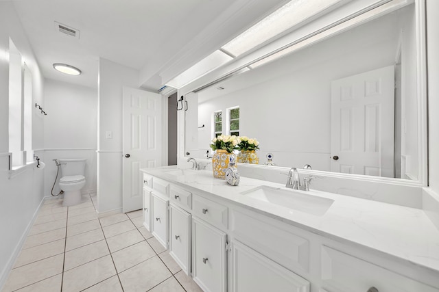 bathroom featuring a sink, tile patterned flooring, toilet, and double vanity