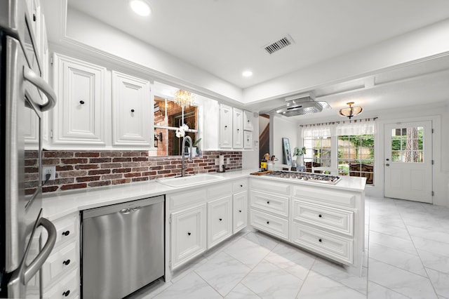 kitchen featuring appliances with stainless steel finishes, a sink, marble finish floor, a peninsula, and visible vents