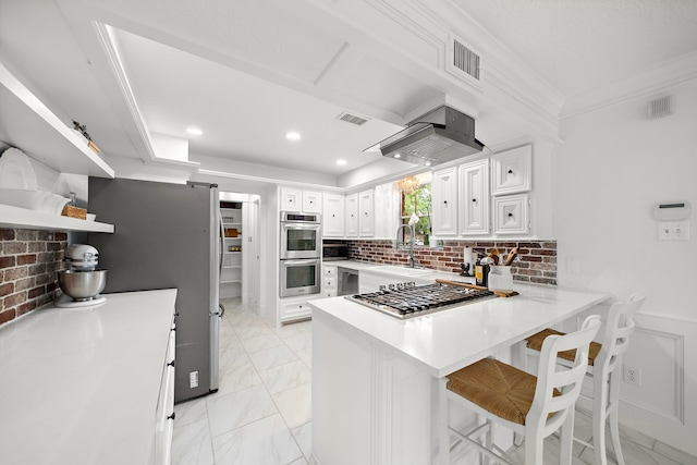 kitchen featuring visible vents, appliances with stainless steel finishes, a sink, light countertops, and a peninsula