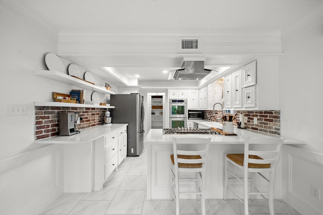 kitchen featuring visible vents, a peninsula, range hood, light countertops, and stainless steel appliances