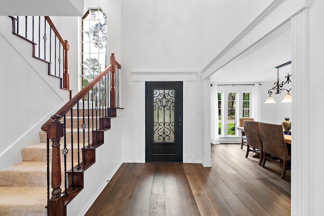 foyer entrance with baseboards, dark wood-style flooring, and stairway