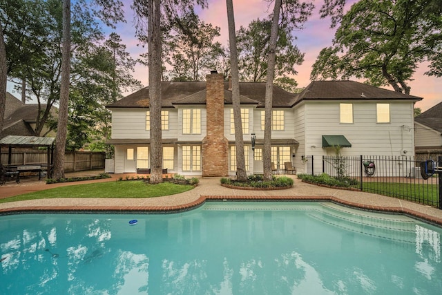 exterior space featuring a fenced in pool, fence, a chimney, and a yard