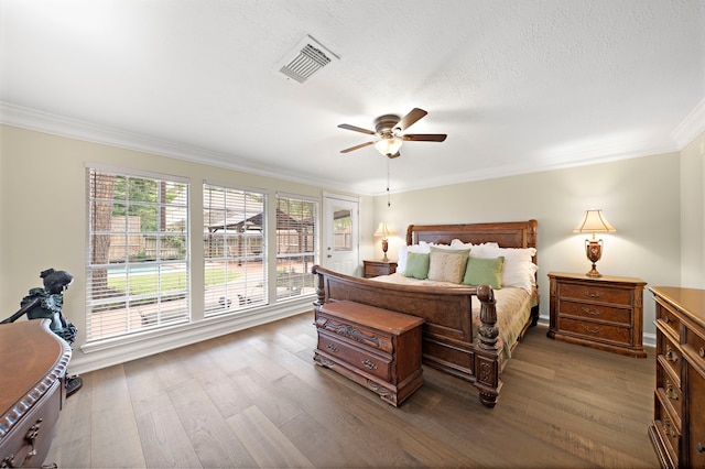 bedroom featuring visible vents, a ceiling fan, crown molding, and dark wood-style floors