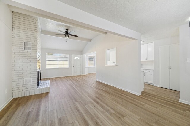 unfurnished living room featuring a ceiling fan, baseboards, vaulted ceiling with beams, and light wood-style floors