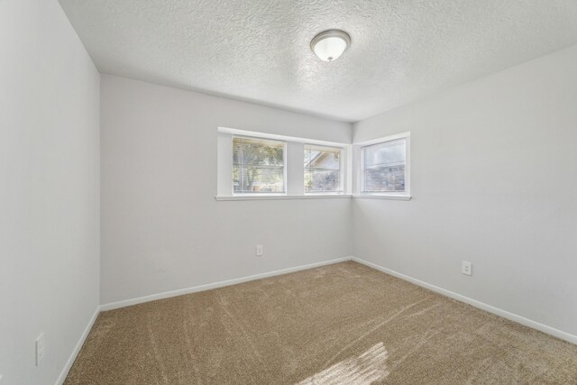 carpeted empty room with baseboards and a textured ceiling