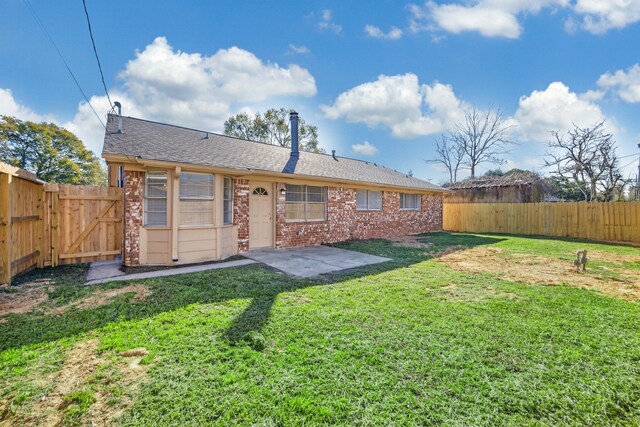 back of house featuring brick siding, a fenced backyard, a patio area, and a yard
