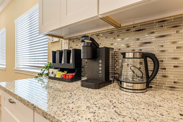 details with light stone counters, tasteful backsplash, and white cabinets