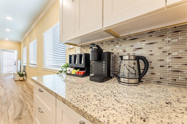 kitchen featuring ornamental molding, recessed lighting, white cabinets, light stone counters, and backsplash