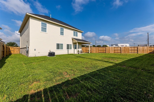 back of house featuring a lawn, a fenced backyard, and central air condition unit
