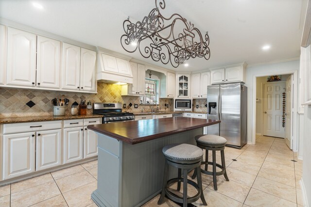 kitchen featuring a notable chandelier, a breakfast bar, wood counters, stainless steel appliances, and tasteful backsplash
