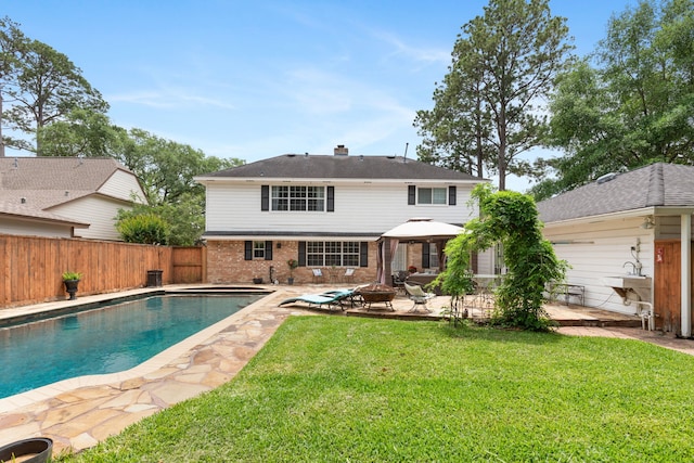 rear view of property featuring a yard, a patio, brick siding, and a fenced backyard