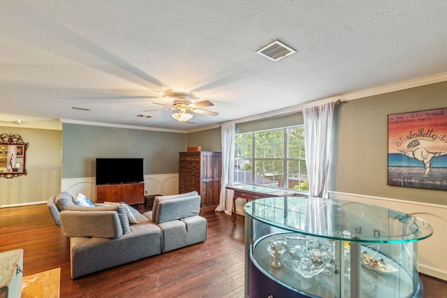 living area featuring wainscoting, crown molding, visible vents, and wood finished floors