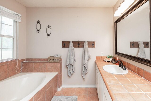 bathroom featuring vanity, tile patterned flooring, a bath, and a healthy amount of sunlight