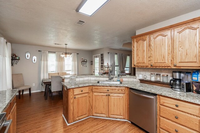 kitchen with visible vents, dishwasher, a sink, light wood finished floors, and a peninsula