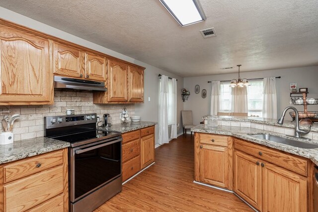 kitchen featuring stainless steel range with electric stovetop, a sink, light wood finished floors, an inviting chandelier, and under cabinet range hood