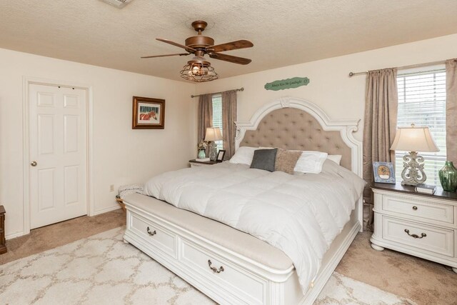 bedroom with light colored carpet, a textured ceiling, and ceiling fan