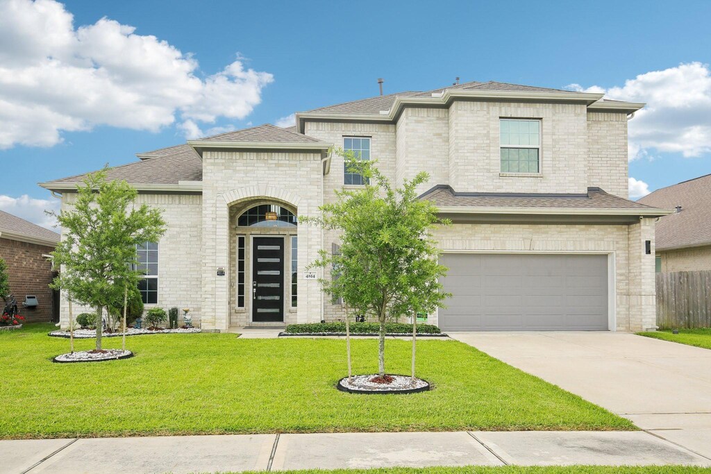 4814 Goldeneye Dr, Baytown, TX 77521 - french country home featuring an attached garage, a front lawn, driveway, and brick siding