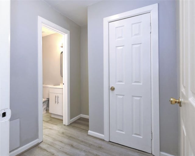 hall with baseboards and light wood finished floors