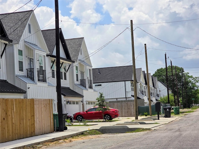 view of side of home featuring fence, a shingled roof, a garage, a standing seam roof, and metal roof
