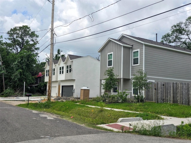 view of property exterior featuring fence, board and batten siding, and an attached garage