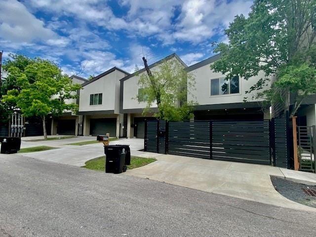 view of front facade with fence, stucco siding, driveway, and a garage