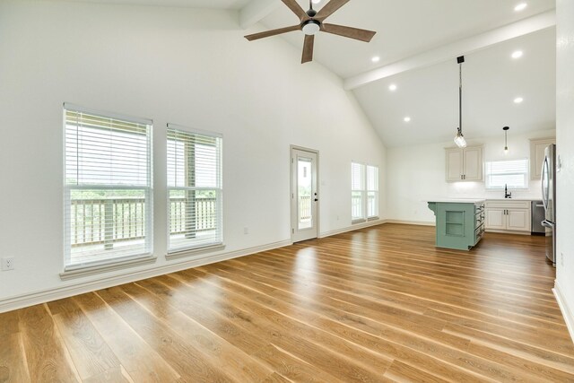 unfurnished living room featuring light wood-style floors, ceiling fan, high vaulted ceiling, and beamed ceiling