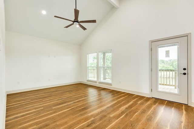 spare room with baseboards, ceiling fan, wood finished floors, and high vaulted ceiling