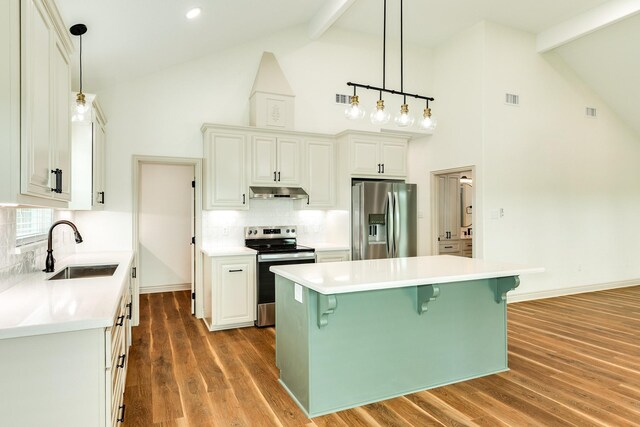 kitchen with a sink, beamed ceiling, high vaulted ceiling, and stainless steel appliances