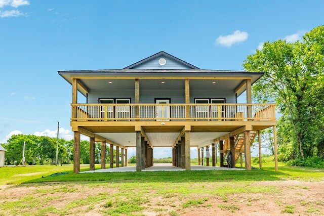 rear view of property with a carport, a yard, a deck, and stairway