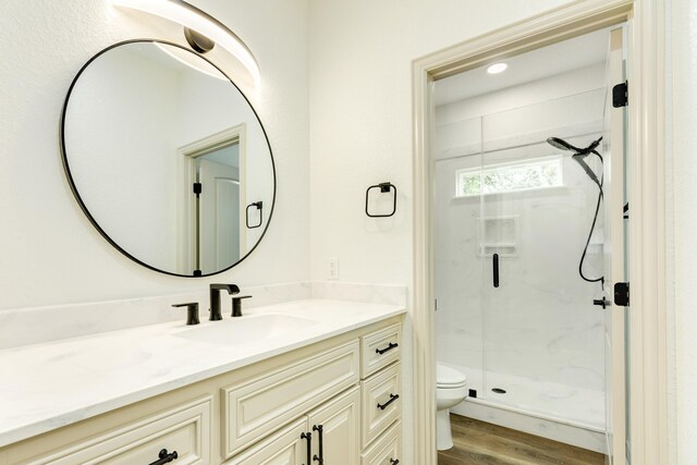 bathroom featuring a marble finish shower, vanity, toilet, and wood finished floors